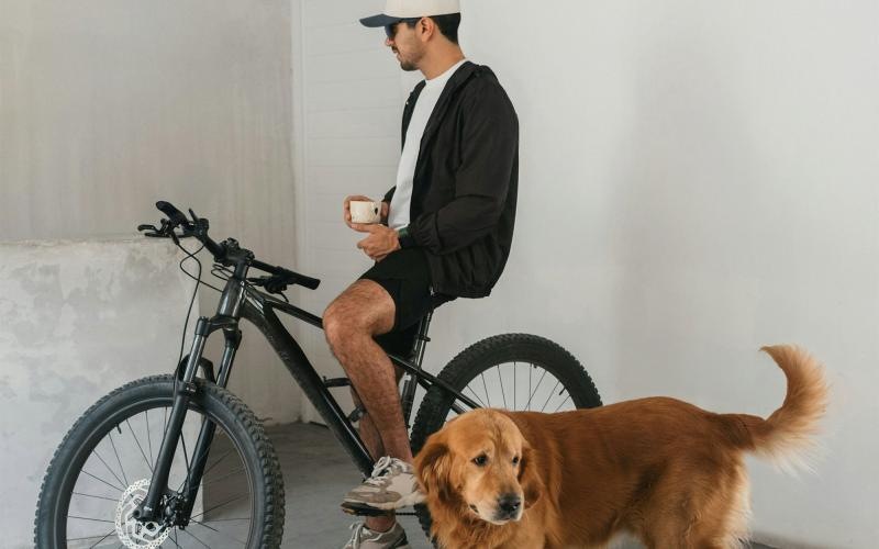 a man sitting on a bike next to a dog